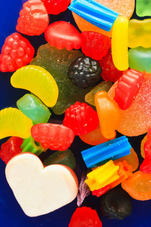 A handful of colorful, chewy candy on a blue plateの写真素材