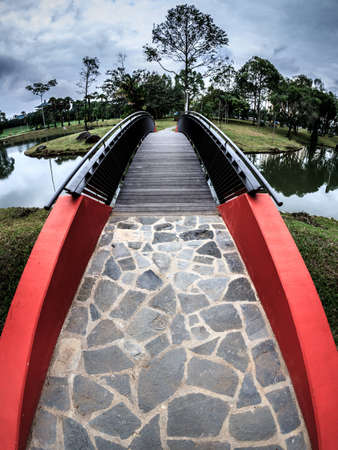 A bridge over a calm mirror like pond under a brewing stormの写真素材