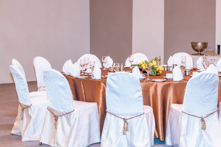 An event dinner set up with white seat covers and bronze table cloth.の写真素材