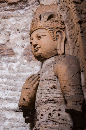Giant reddish brown stone Buddha scultpure in one of the main caves at the Yungang Grottos.の写真素材