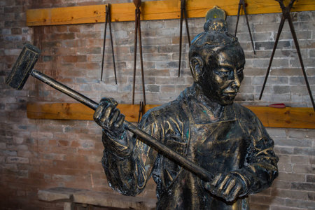 Close up of a metal statue of a blacksmith in his workshop.の写真素材
