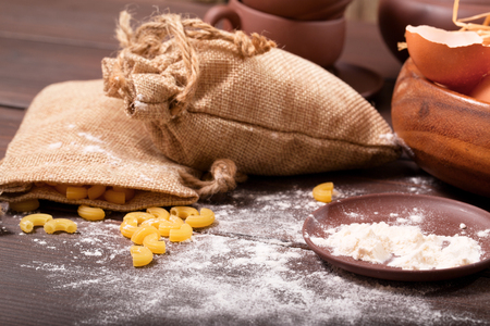 Products on a kitchen rural table. Macaroni in a sack, eggs, flour. A background from old boards, rural styleの写真素材