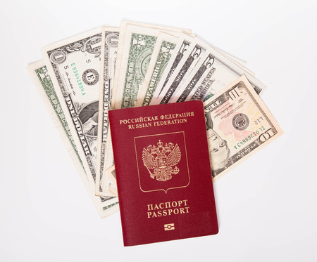 The Russian passport in a red cover lies on a pile of notes (dollars)の写真素材