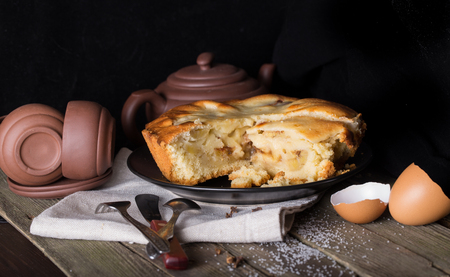 Piece of pie and pottery for tea on an old wooden table. Style "dark and moody", close up, small depth of sharpnessの写真素材