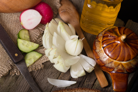 The cut vegetables on an old wooden table. Rural style, close up, dark background. A flower from a bulb, radishes and a cucumber, the cut with krudochka, vegetable oil, a knife, breadの写真素材