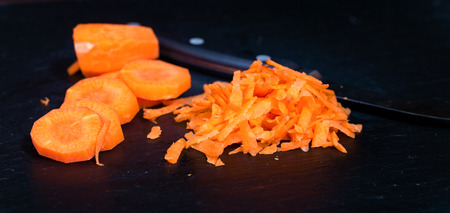The cut crushed carrots on a black board. A black background, carrots it is cut in the different ways. Close up, small depth of sharpnessの写真素材