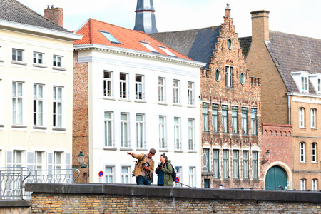 BRUGES, BELGIUM - JUNE 7, 2017: Buildings on the canal embankment, in the distance unknown tourists. A low point of shooting, the distorted prospect, in the foreground a pavement stone blocksのeditorial素材