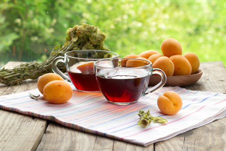 Herbal tea and apricots on a wooden table. Natural lighting, summer day. Close up, selective focus, rural styleの写真素材