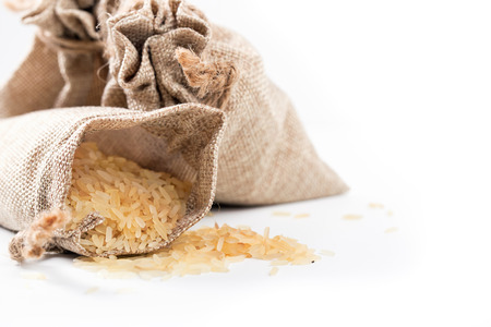 The bags filled with rice and scattered rice. The close up, selective focus, one of bags is untied and has fallen. White backgroundの写真素材