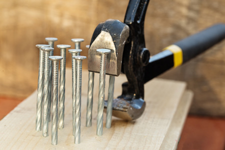 Pincers and nails close up. Nails are hammered into a board, pincers has grabbed and are ready to...
