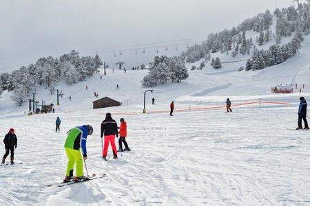 PYRENEES, ANDORRA - FEBRUARY 6, 2018: Skiers stand on ski resort at the beginning of a slope. The gentle slope for beginners, was eaten in snow on a backgroundのeditorial素材