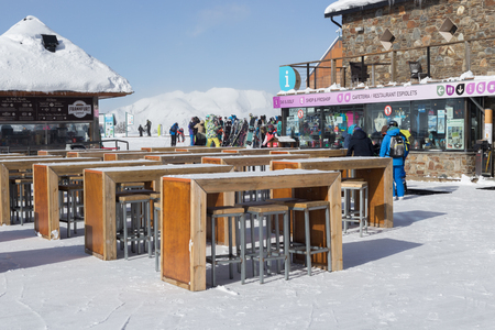 PYRENEES, ANDORRA - FEBRUARY 6, 2018: Tourists near the tables of the open-air cafe terrace in the ski resort. Near the store with sports equipment and ski racksのeditorial素材