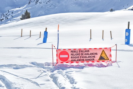 The sign of the danger of an avalanche is set in the mountains. The inscription in four languages "The danger of an avalanche", a sign installed in the ski resort in Andorra, the Pyreneesの写真素材