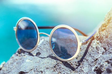 Round sunglasses with blue glasses on the stone.の写真素材