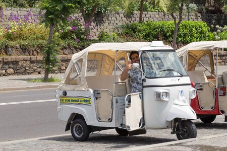FUNCHAL, MADEIRA, PORTUGAL - JULY 22, 2018: The driver of the tourist electric vehicle welcomes...