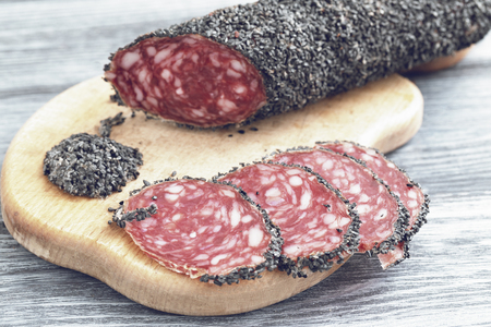 Uncooked smoked sausage with a red cut on a wooden cutting boardの写真素材
