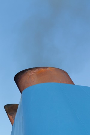 Smoke from the blue pipe of the ship against the blue sky.の写真素材
