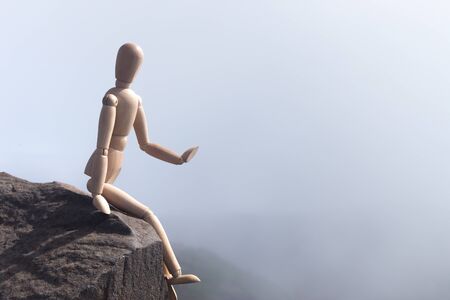 A wooden doll sits on the edge of the abyss.の写真素材