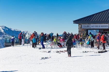 PYRENEES, ANDORRA - FEBRUARY 13, 2019: Unknown tourists at a ski resort in a cafe on the side of a...