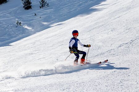 PYRENEES, ANDORRA - FEBRUARY 16, 2019: A boy skiing in slalom uniform on a mountainside makes a sharp turnのeditorial素材