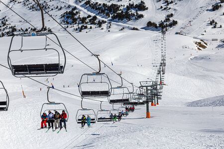 YRENEES, ANDORRA - FEBRUARY 15, 2019: Tourists athletes, skiers and snowboarders on the chair lift of a ski resort.のeditorial素材