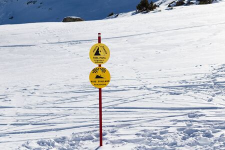 Signs in the mountains at a ski resort with hazard warnings.
