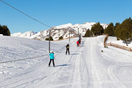 PYRENEES, ANDORRA - FEBRUARY 16, 2019: Athletes skiers climb a gentle slope on a ski lift.のeditorial素材