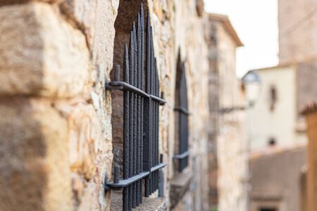 Iron grate on the window of an old stone house in Spain. Close-up, selective focus