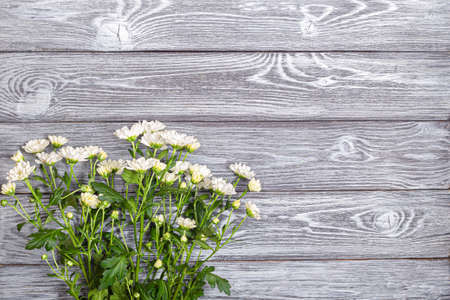 A bouquet of white bush chrysanthemums on a wooden tableの写真素材