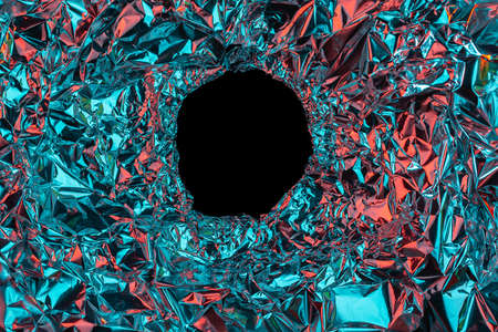 Abstract red-blue background of crumpled foil with a hole in the middle.