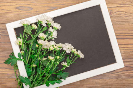 The frame with empty space inside rests on a wooden table.