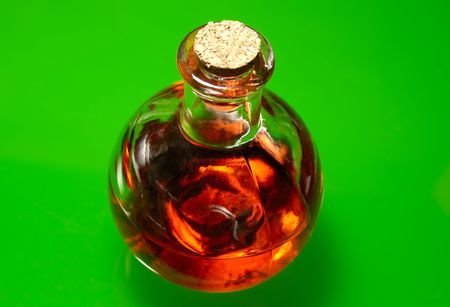 Photo of Vintage Bottle With Red Liquid on a Green Backgroundの写真素材
