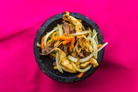 Stir fry beef with onion and carrot in black bowl on pink backgroundの写真素材