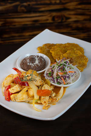 Fried chicken with vegetables and sauce on a white plateの写真素材