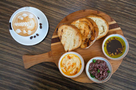 Coffee with bread and hummus on a wooden background.