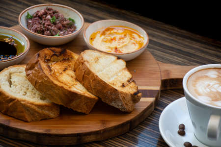 Breakfast with coffee and bread on a wooden table in a cafeの写真素材