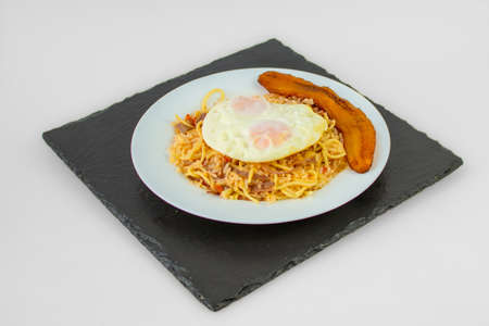 Pasta with fried egg on a white plate on a black backgroundの写真素材