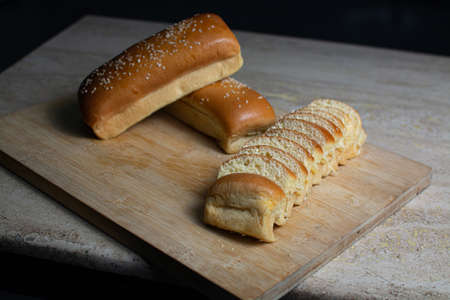 Delicious bread with sesame seeds on a wooden cutting board.の写真素材