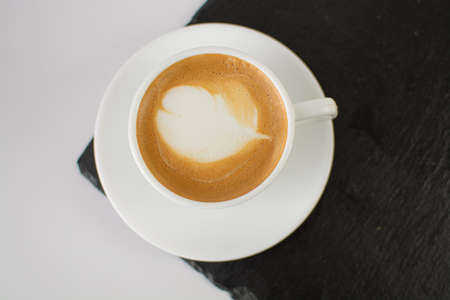 Cup of coffee with heart shape latte art on white backgroundの写真素材