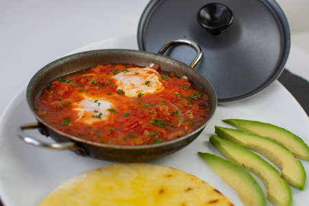 Shakshuka in a frying pan with avocado and tomatoes.の写真素材