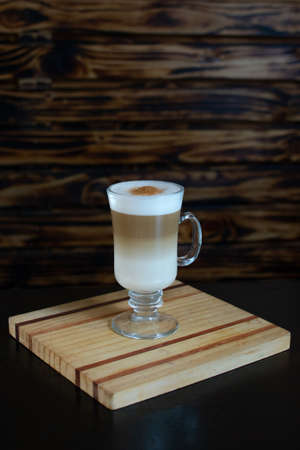 Cappuccino coffee in a glass cup on a wooden backgroundの写真素材