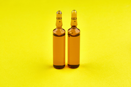 Brown ampoules with medicine on yellow background.の写真素材