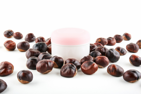 Cosmetic jar and chestnuts on white background.の写真素材