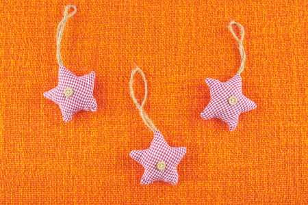Star shaped Christmas tree decorations on orange hessian. New Year toy