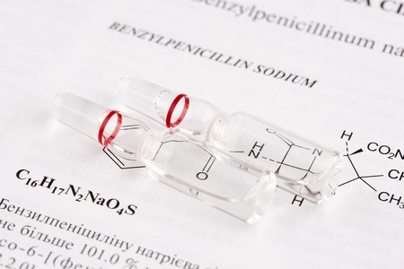 Two ampoules on book page with chemical formula.の写真素材