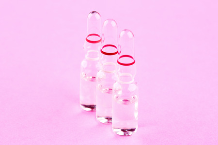 Ampoules with medicine on pink background.
