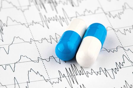 Close-up photo of white and blue pills on EKG graph.