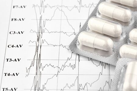 Blister with white pills on EKG graph. Medicine.