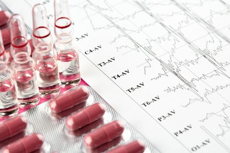 Ampoules, blister with red pills and EKG graph.