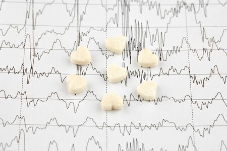 Seven heart shaped pills on EKG graph. Medicine.